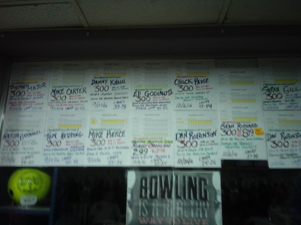 In recent years, the pro shop has had a tradition of putting the desk printouts of 300 games and 800 series (and some other notable efforts) on the pro shop window, extending to the walls around the pro shop later in the year. This was the state of the window on Halloween night, 2016.